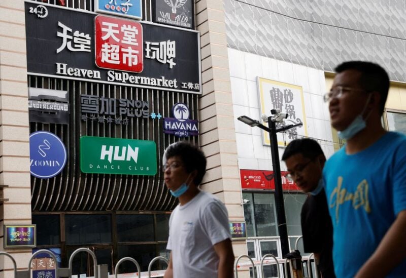 People walk past a sign of the Heaven Supermarket bar, where a coronavirus disease (COVID-19) outbreak emerged, in Chaoyang district of Beijing, China June 13, 2022. REUTERS/Carlos Garcia Rawlins