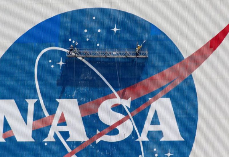 Workers pressure wash the logo of NASA on the Vehicle Assembly Building before SpaceX will send two NASA astronauts to the International Space Station aboard its Falcon 9 rocket, at the Kennedy Space Center in Cape Canaveral, Florida, U.S., May 19, 2020. REUTERS/Joe Skipper