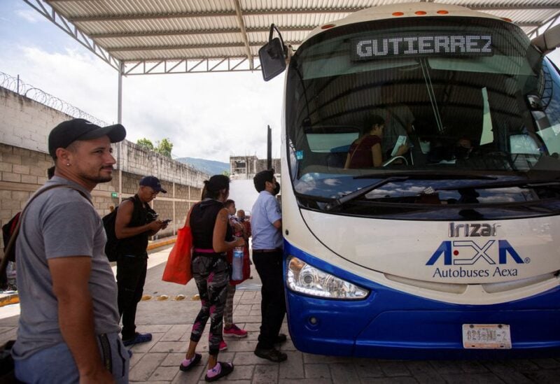 Migrants who left a caravan, after receiving their documents to cross the country, board a bus at a bus station in Huixtla, Mexico