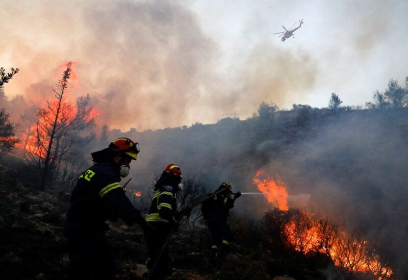 Firefighters and volunteers try to extinguish a wildfire near Vari, south of Athens