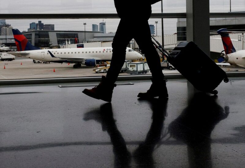 FILE PHOTO: A passenger walks past a Delta Airlines plane at a gate at Logan International Airport in Boston, Massachusetts, U.S., January 3, 2022. REUTERS/Brian Snyder/File Photo