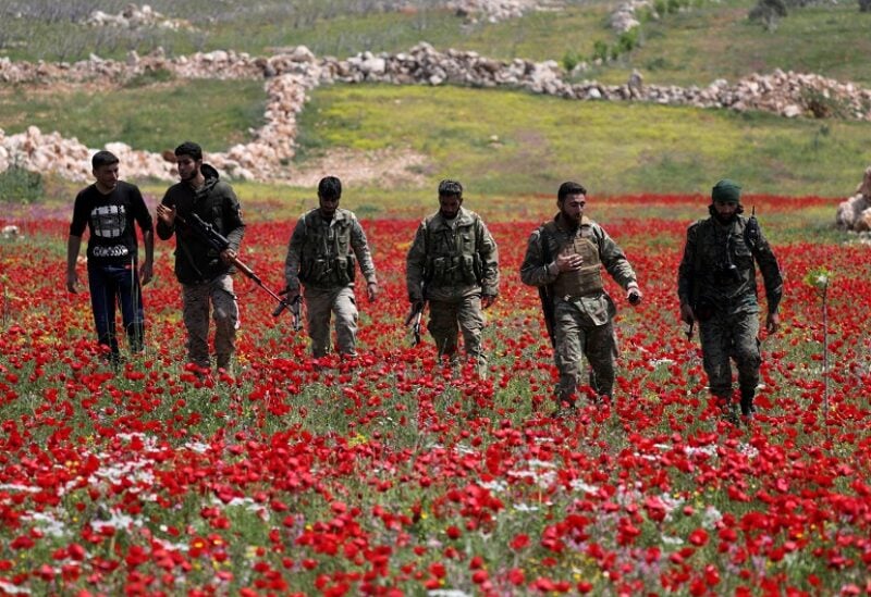 FILE PHOTO: Turkey-backed Syrian rebel fighters walk in a field of flowers in Jabal al-Zawiya in Idlib's southern countryside, amid concerns about the spread of the coronavirus disease (COVID-19), Syria April 15, 2020. Picture taken April 15, 2020. REUTERS/Khalil Ashawi/File Photo