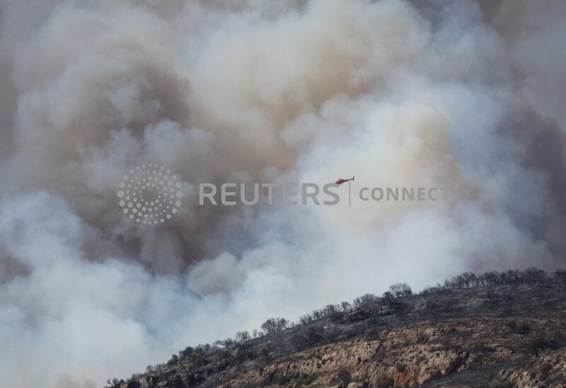 A helicopter flies next to a smoke during a wildfire near Artesa de Segre, Spain, June 18, 2022. REUTERS/Albert Gea