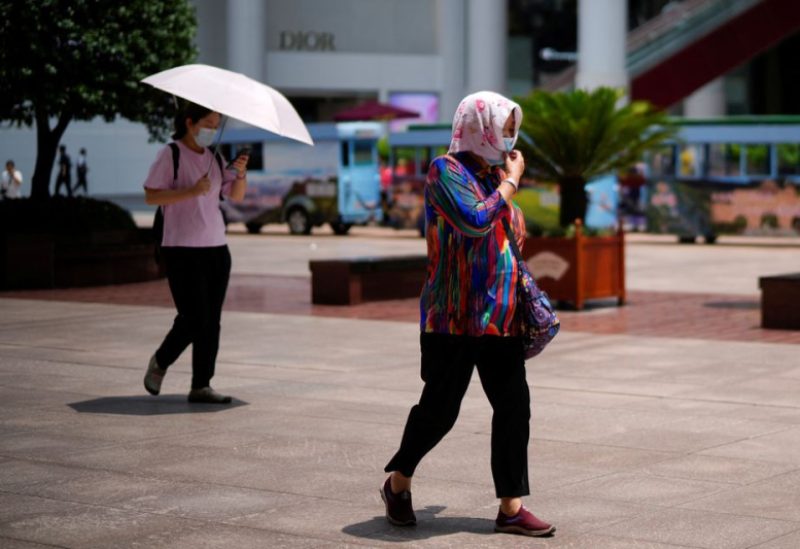 A woman covers herself with a towel and mask on a hot day, following a coronavirus disease (COVID-19) outbreak in Shanghai, China July 11, 2022. REUTERS/Aly Song