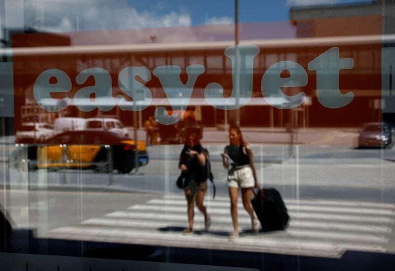 Passengers reflected on a glass with an Easyjet logo on it walk at Josep Tarradellas Barcelona-El Prat Airport during an Easyjet's cabin crew strike, in Barcelona, Spain, July 1, 2022. REUTERS/Albert Gea