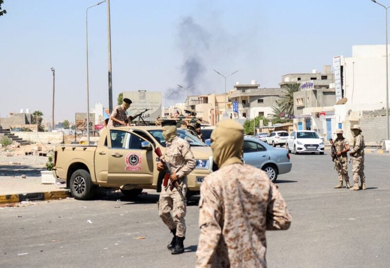 Members of the Libyan armed unit, 444 Brigade, backing the Government of National Unity (GNU) and its Prime Minister Abdulhamid al-Dbeibah, set up a checkpoint as smoke rises in the background in Ain Zara area in Tripoli, Libya, July 22, 2022. REUTERS/Hazem Ahmed