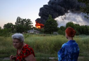 Local residents look on as smoke rises after shelling during Ukraine-Russia conflict in Donetsk, Ukraine July 7, 2022