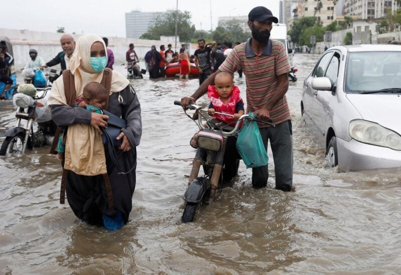 A family wades through a flooded road during the monsoon season in Karachi, Pakistan July 9, 2022