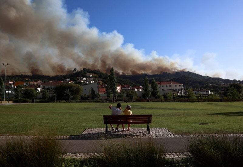People watch as smoke rises from a wildfire in Venda do Pinheiro, Mafra, Portugal, July 31, 2022