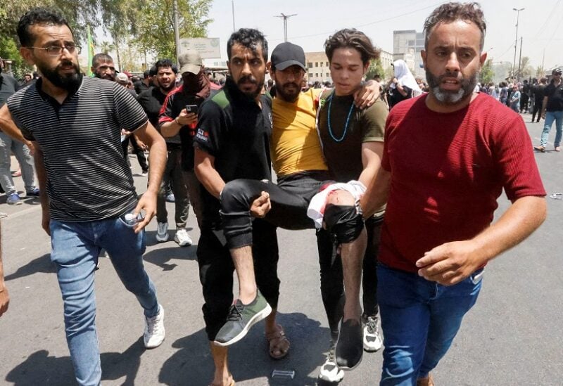Supporters of Iraqi Shi'ite cleric Moqtada al-Sadr carry an injured man during a protest against corruption, near Green Zone, in Baghdad, Iraq July 30, 2022. REUTERS/Ahmed Saad