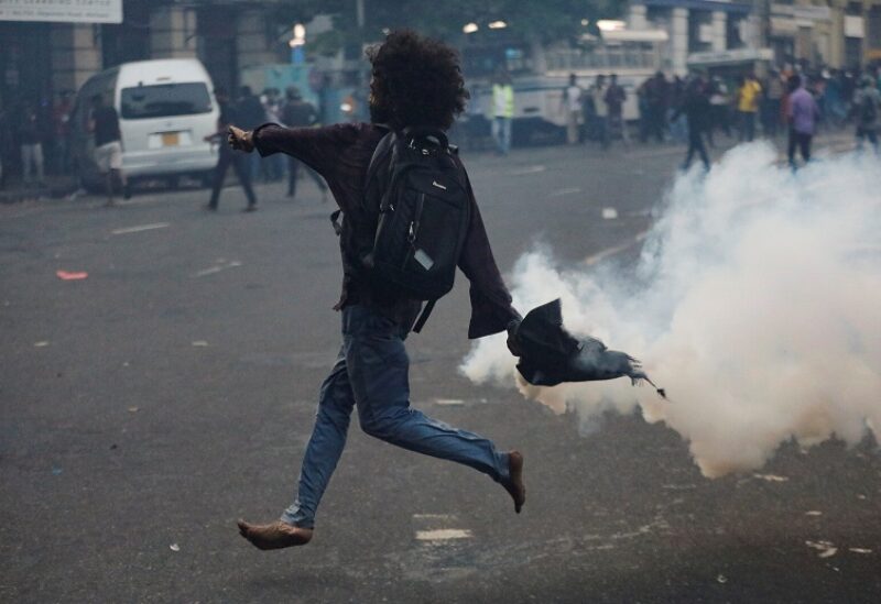 A demonstrator throws back a tear gas towards police members as police use tear gas and water cannons to disperse demonstrators near President's residence during a protest demanding the resignation of President Gotabaya Rajapaksa, amid the country's economic crisis, in Colombo, Sri Lanka, July 8, 2022. REUTERS/Dinuka Liyanawatte