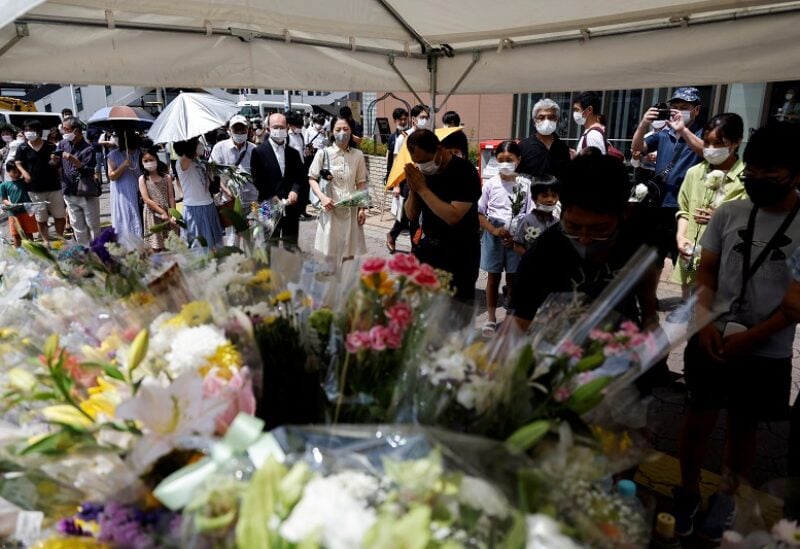 People queue up to offer flowers and pray at the site where late former Japanese Prime Minister Shinzo Abe was shot while campaigning for a parliamentary election, near Yamato-Saidaiji station in Nara, Japan, July 9, 2022. REUTERS/Issei Kato