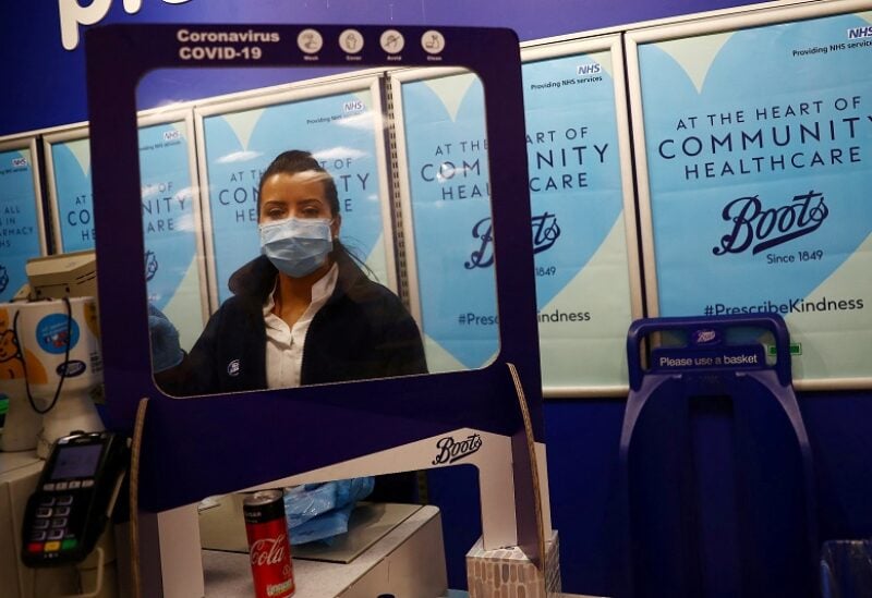 FILE PHOTO: A Boots employee wearing a face mask works at a counter behind a protective screen at a store in London, as the spread of the coronavirus disease (COVID-19) continues, London, Britain, April 8, 2020. REUTERS/Hannah McKay/File Photo