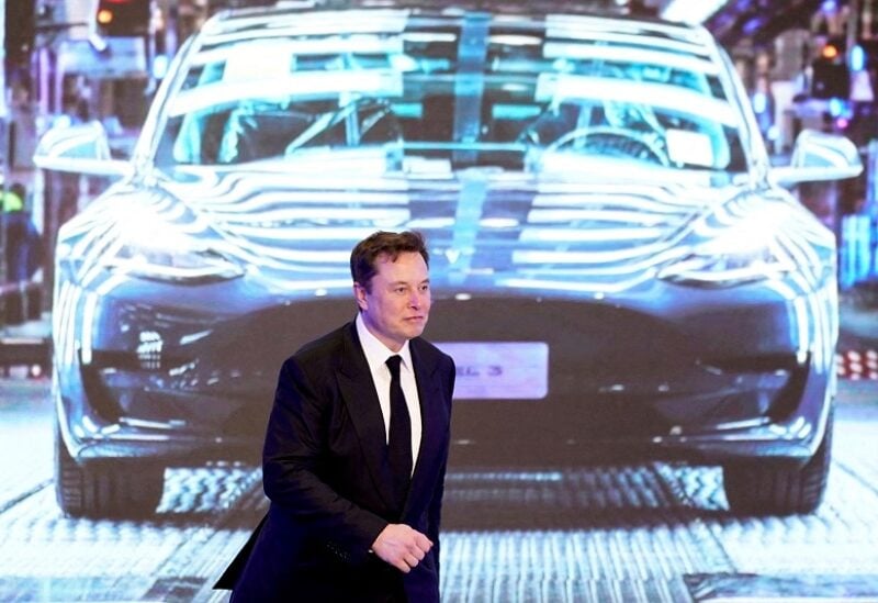 Elon Musk walks next to a screen showing an image of Tesla Model 3 car during an opening ceremony for Tesla China-made Model Y program in Shanghai