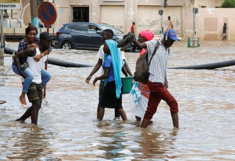 Residents make their way through a flooded street after torrential rain caused intense flooding in Dakar, Senegal August 6, 2022. REUTERS/Ngouda Dione