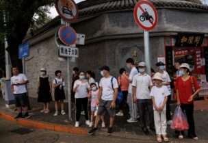 People wear face masks as they stand in a street following a coronavirus disease (COVID-19) outbreak, in Beijing, China, August 3, 2022. REUTERS/Thomas Peter/File Photo