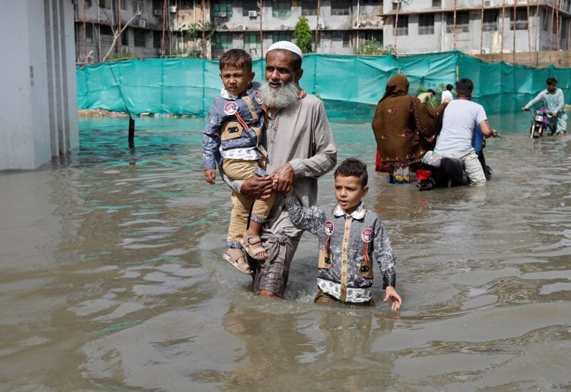 Residents wade through a flooded street during the monsoon season in Karachi, Pakistan July 11, 2022. REUTERS/Akhtar Soomro