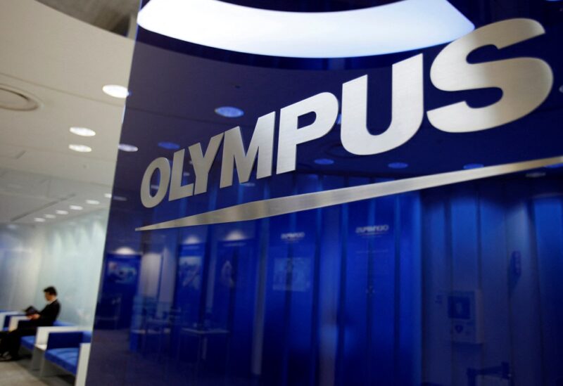 A man sits near the Olympus Corp logo at company headquarters in Tokyo June 19, 2012. REUTERS/Yuriko Nakao/File Photo