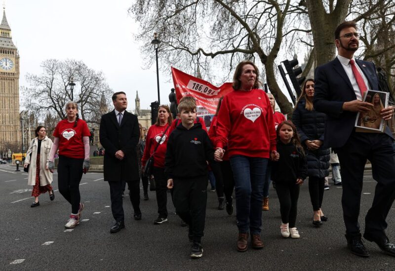 Attendees march past the Big Ben to the Downing Street on national day of reflection to mark the 1 year anniversary of The National Covid Memorial Wall creation, in London, Britain March 29, 2022. REUTERS