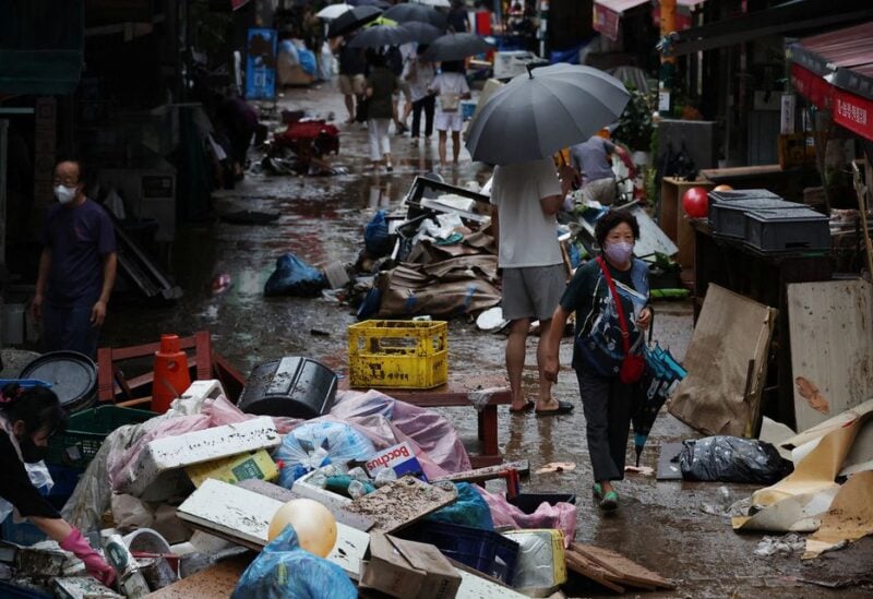 People make their way through a road that was flooded after torrential rain, at a traditional market in Seoul, South Korea, August 9, 2022