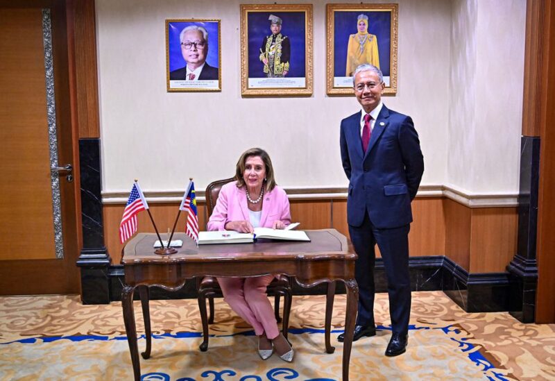 U.S. House of Representatives Speaker Nancy Pelosi sits while signing the guest book as Malaysia's Parliament Speaker Azhar Azizan Harun stands next to her