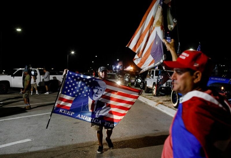 A supporter of former U.S. President Donald Trump holds a flag as he and others gather outside his Mar-a-Lago home after Trump said that FBI agents raided it, in Palm Beach, Florida, U.S., August 8, 2022. REUTERS/Marco Bello