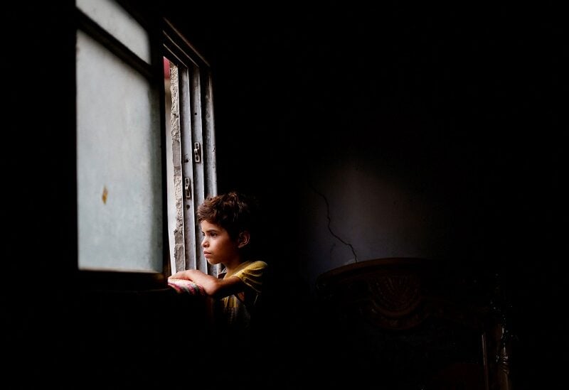 A Palestinian boy looks out of the window of his family house amid a heatwave and lengthy power cuts in Gaza City August 1, 2022. REUTERS/Mohammed Salem