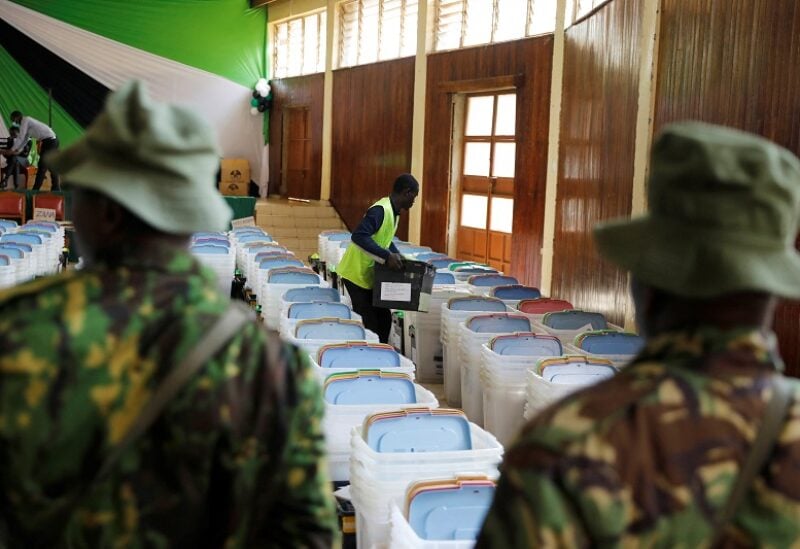 Police officers watch as an employee of the Independent Electoral and Boundaries Commission (IEBC) arranges ballot boxes and election materials at a tallying centre in Eldoret, Kenya, August 8, 2022. REUTERS/Baz Ratner