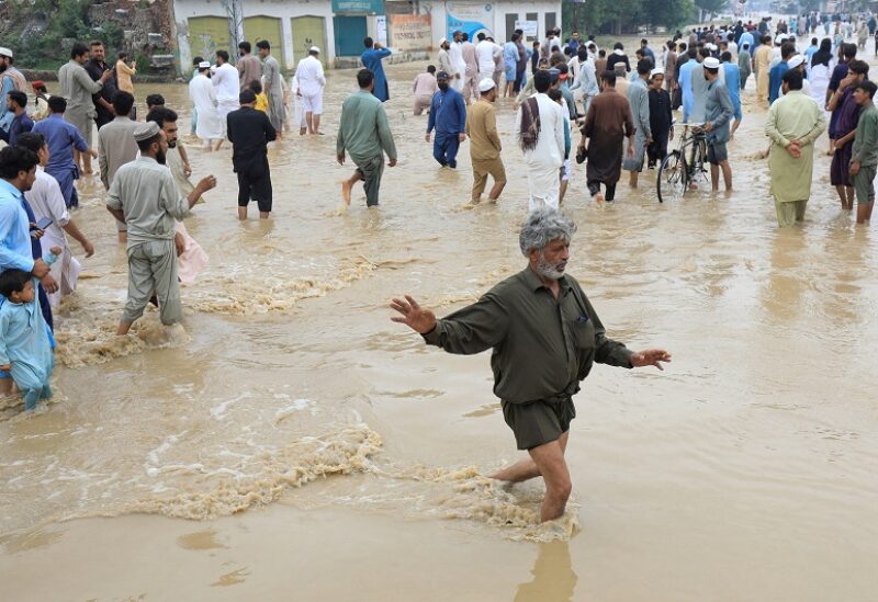 A man balances himself as he, along with others, walks on a flooded road, following rains and floods during the monsoon season in Charsadda, Pakistan August 27, 2022. REUTERS/Fayaz Aziz