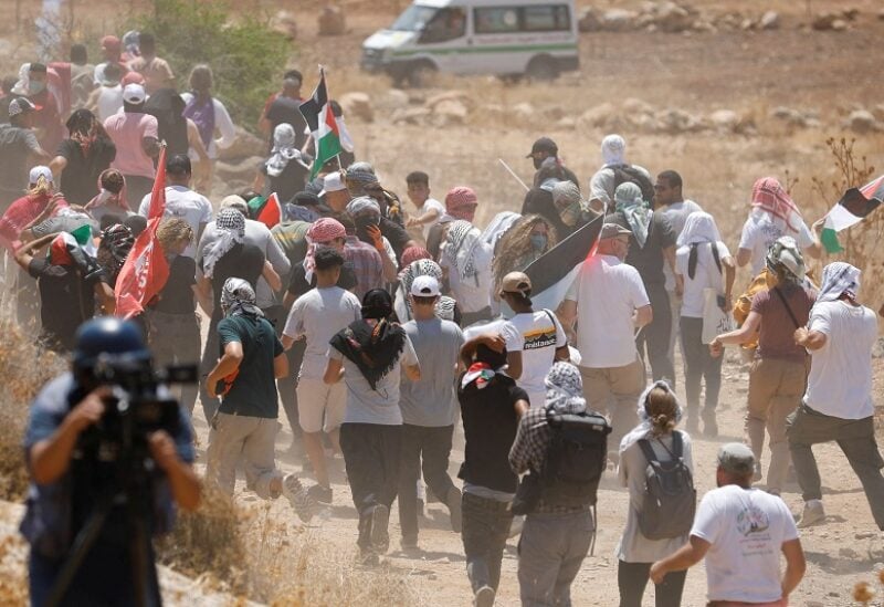 Palestinian demonstrators run as people clash with Israeli forces during a protest against Israeli settlement activity in Beit Dajan, in the Israeli-occupied West Bank August 2, 2022. REUTERS/Raneen Sawafta