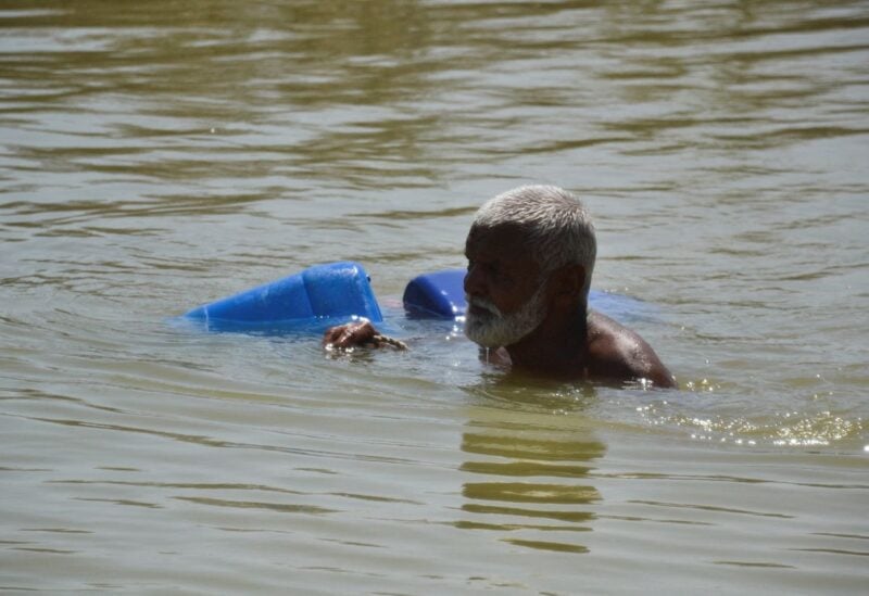 A man, displaced because of the floods, wades through flood water to fill the canisters, following rains and floods during the monsoon season in Sehwan, Pakistan September 20, 2022. REUTERS/Stringer/File Photo