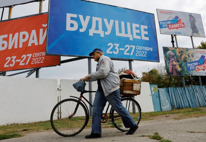 A man walks with his bicycle past banners informing about a referendum on the joining of Russian-controlled regions of Ukraine to Russia, in the Russian-controlled city of Melitopol in the Zaporizhzhia region, Ukraine September 26, 2022. The banner (C) reads: "Future. 23-27 September 2022". REUTERS/Alexander Ermochenko