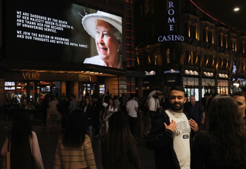 People walk in front of an image of Britain's Queen Elizabeth in the street, following her death, in London, Britain, September 11, 2022. REUTERS/Marko Djurica
