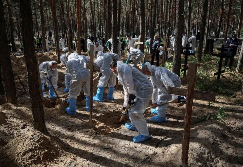 Members of Ukrainian Emergency Service work at a place of mass burial during an exhumation, as Russia's attack on Ukraine continues, in the town of Izium, recently liberated by Ukrainian Armed Forces, in Kharkiv region, Ukraine September 19, 2022. REUTERS/Gleb Garanich