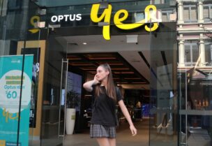A woman uses her mobile phone as she walks past in front of an Optus shop in Sydney, Australia, February 8, 2018. REUTERS/Daniel Munoz/File Photo