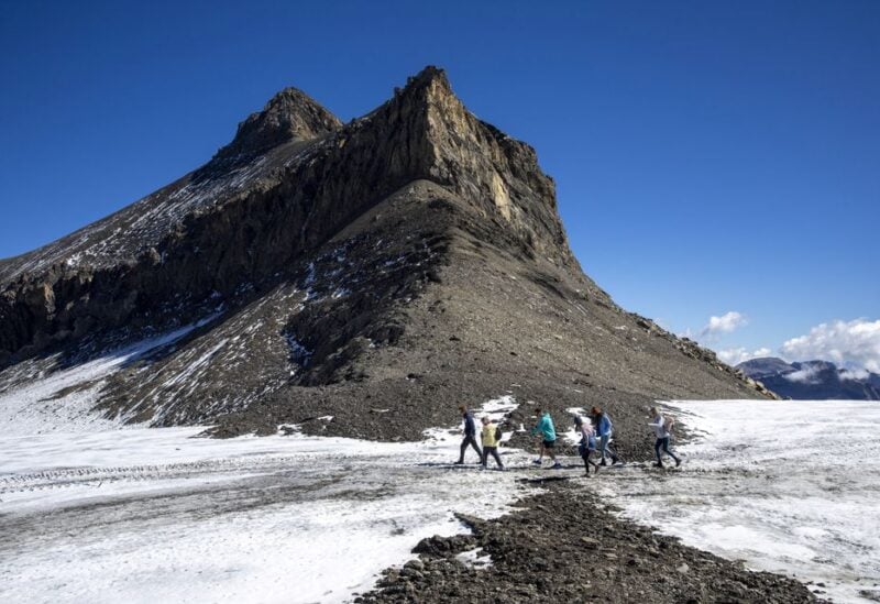 Hikers walk past the newly uncovered Zanfeluron path, as a split of the Sex-Rouge and the Zanfleuron Glacier revealed the path for the first time in 2000 years due to this summer heatwave, at Glacier 3000 in Les Diablerets, Switzerland, September 11, 2022. REUTERS/Denis Balibouse