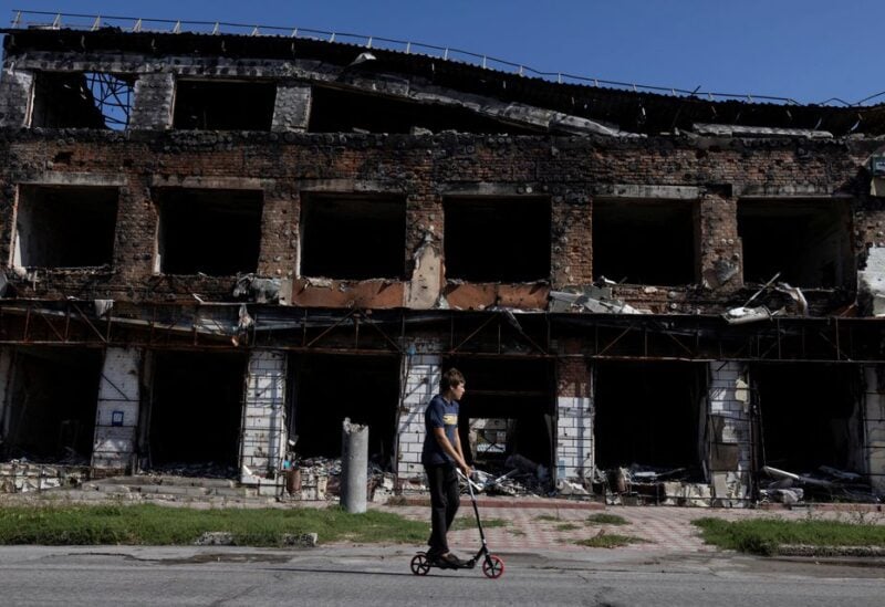 A boy rides his scooter past a destroyed building, as Russia's attack on Ukraine continues, in the town of Izium, recently liberated by Ukrainian Armed Forces, in Kharkiv region, Ukraine September 18, 2022. REUTERS/Umit Bektas