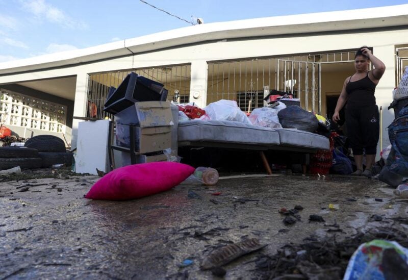 A woman looks at her water-damaged belongings after flooding caused by Hurricane Fiona tore through her home in Toa Baja, Puerto Rico, Tuesday, Sept. 20, 2022. (AP Photo/Stephanie Rojas)