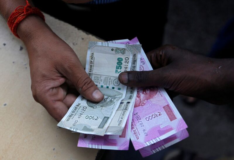 A customer hands Indian currency notes to an attendant at a fuel station in Mumbai, India, August 13, 2018. REUTERS/Francis Mascarenhas/File Photo