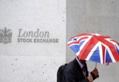 A worker shelters from the rain under a Union Flag umbrella as he passes the London Stock Exchange in London, Britain, October 1, 2008. REUTERS/Toby Melville