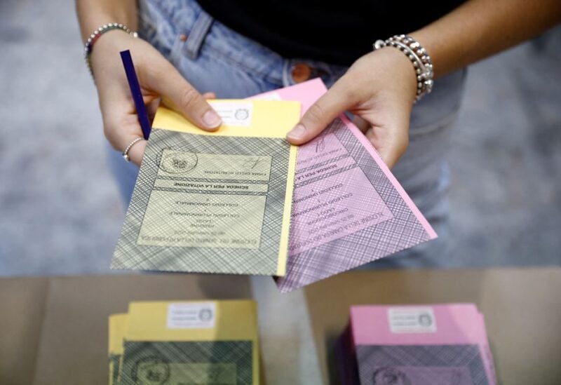 A person holds out ballots at a polling station during the snap election, in Rome, Italy, September 25, 2022. REUTERS