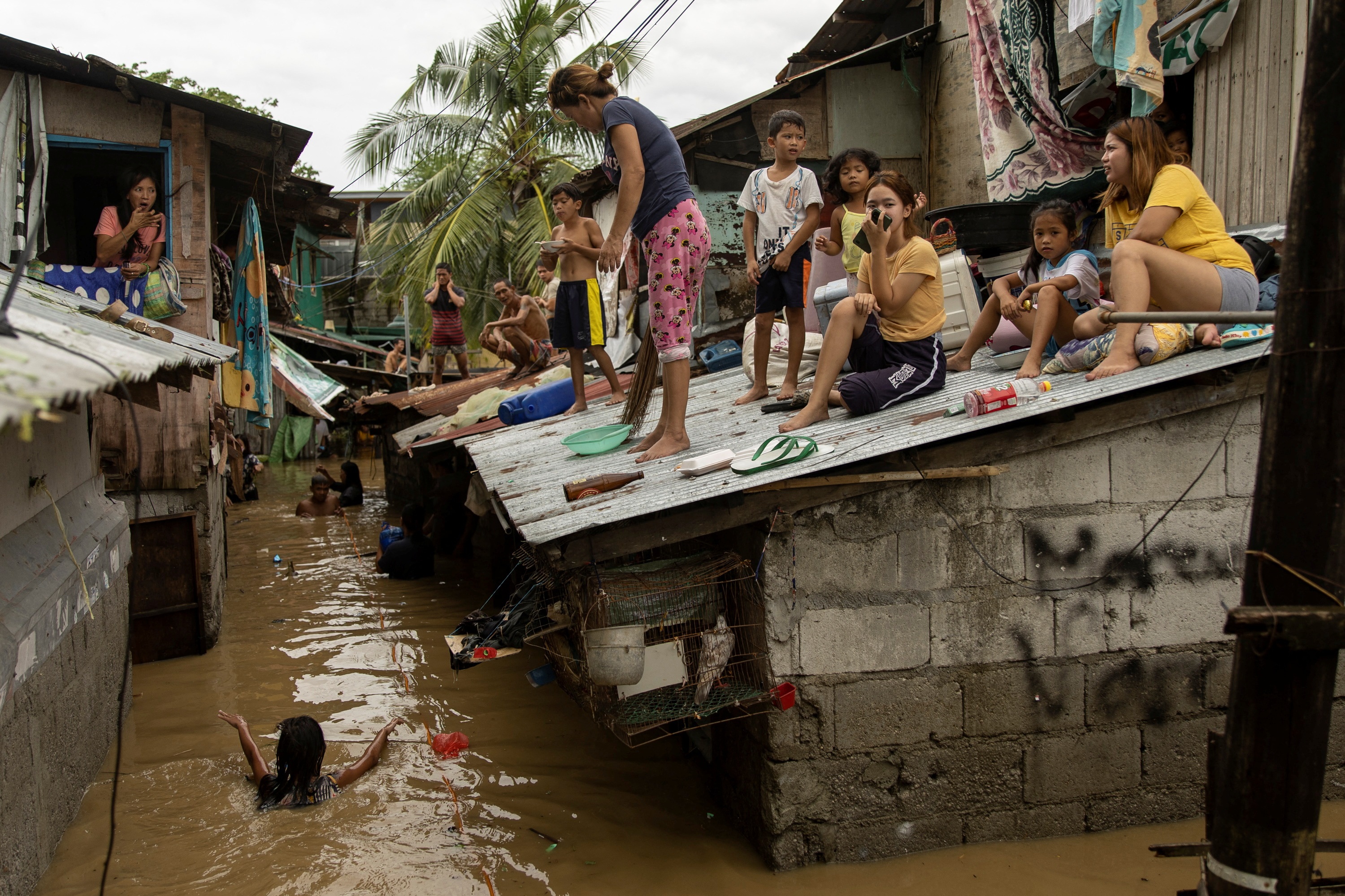 Residents wait on the roof of their homes, for flooding to subside after Super Typhoon Noru, in San Miguel, Bulacan province, Philippines, September 26, 2022. REUTERS/Eloisa Lopez