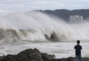 A man looks at a high wave caused by Typhoon Hinnamnor in Ulsan, South Korea, September 6, 2022. Yonhap via REUTERS ATTENTION EDITORS - THIS IMAGE HAS BEEN SUPPLIED BY A THIRD PARTY. SOUTH KOREA OUT. NO RESALES. NO ARCHIVE.