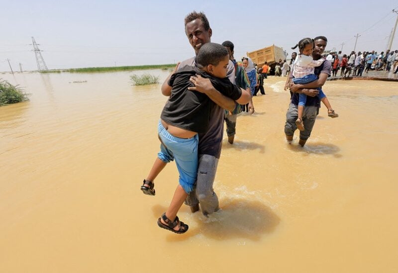 People cross the water during a flood in Al-Managil locality in Gezira state, Sudan, August 23, 2022. REUTERS/Mohamed Nureldin Abdallah TPX IMAGES OF THE DAY