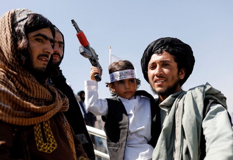 FILE PHOTO: A Taliban member holds his son on the first anniversary of the withdrawal of U.S. troops from Afghanistan, on a street in Kabul, Afghanistan, August 31, 2022. REUTERS/Ali Khara/File Photo