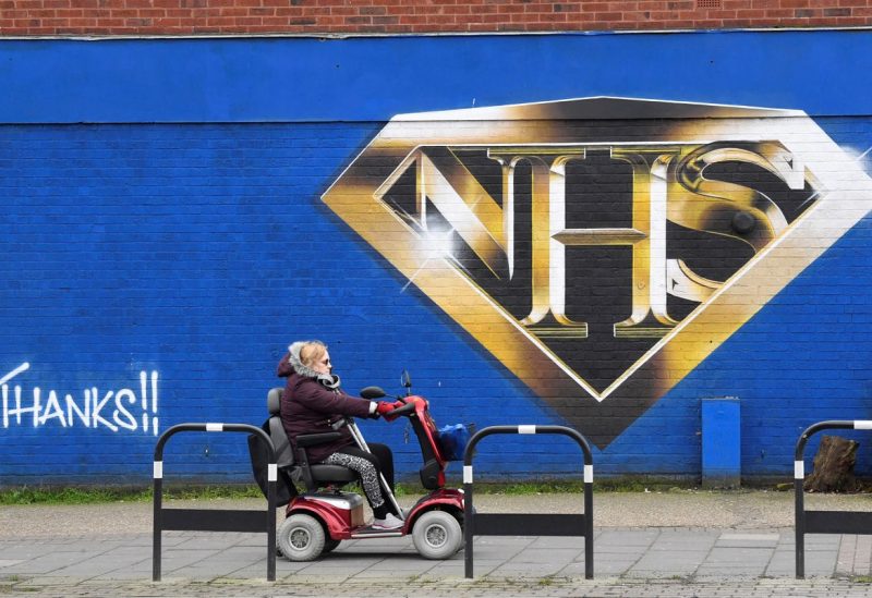 A woman on a mobility scooter drives past a mural praising the NHS (National Health Service) amidst the continuation of the coronavirus disease (COVID-19) pandemic, London, Britain, March 5, 2021. REUTERS/Toby Melville/File Photo