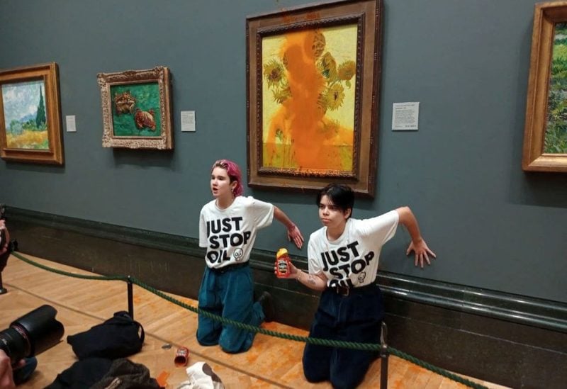 Activists of "Just Stop Oil" glue their hands to the wall after throwing soup at a van Gogh's painting "Sunflowers" at the National Gallery in London, Britain October 14, 2022. Just Stop Oil/Handout via REUTERS