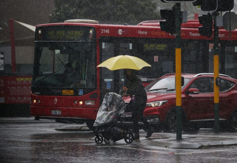 A pedestrian pushing a baby pram crosses a flooding intersection as heavy rains affect Sydney, Australia, October 6, 2022. REUTERS