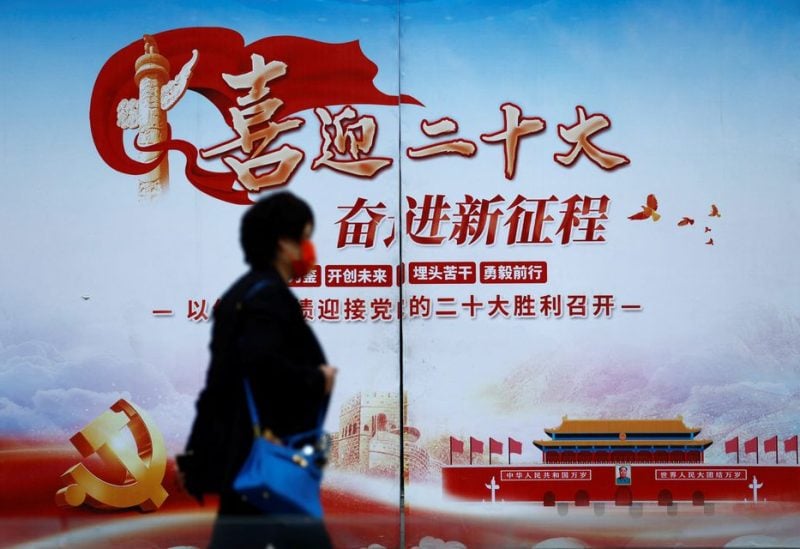 A woman walks past a poster welcoming the 20th National Congress of the Communist Party of China, in Beijing, China October 14, 2022. REUTERS/Tingshu Wang