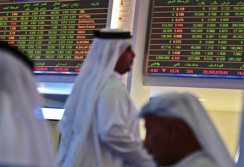 Traders sit below the stock market screens at the Dubai Financial Market in the Gulf emirate.Photographer: KARIM SAHIB/AFP